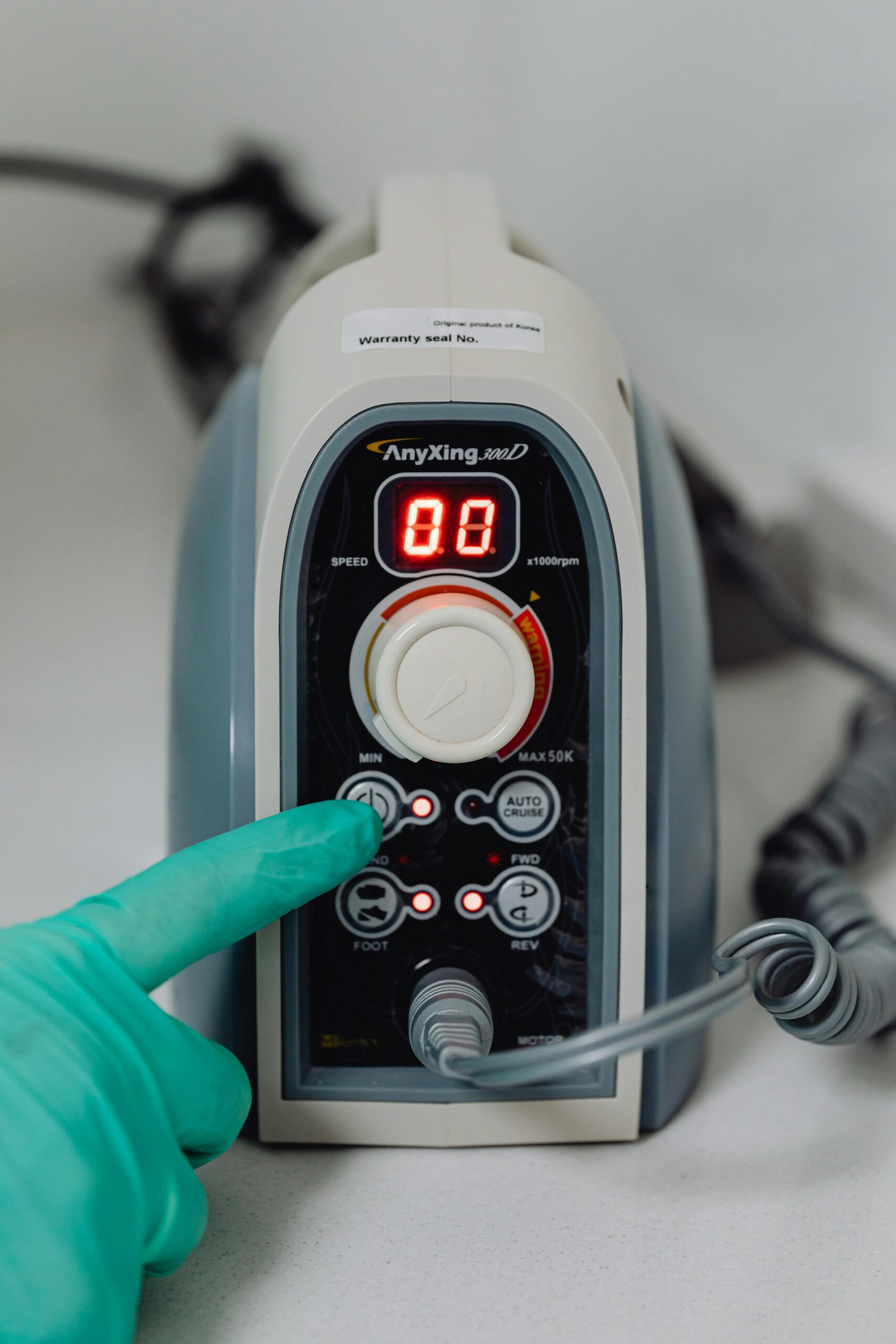 Green-gloved hand adjusting settings on modern medical equipment control panel.